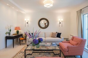 A living room with a sofa, armchair, coffee table, and decorative items. - Terra Di Corfu, Αpartment (Kerkira)