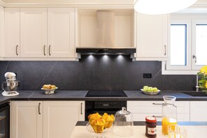 A modern kitchen with white cabinets, a black countertop, and a built-in stove. - Terra Di Corfu, Αpartment (Kerkira)