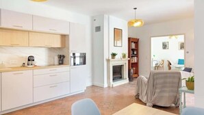 A modern kitchen with white cabinets, a coffee machine, and a fireplace.