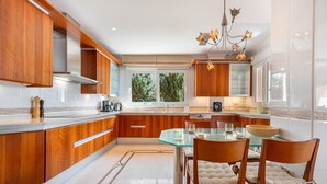 A modern kitchen with wooden cabinets, a glass dining table, and a chandelier.