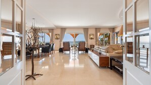A spacious living area with a dining table, chairs, a sofa, and a decorative tree sculpture.