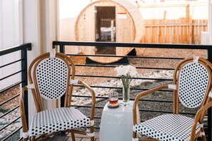 Two wicker chairs with checkered cushions on a balcony with a view of a wooden barrel and a wooden fence. - The Fairway House | Luxe Design, Sauna + Mini Putt (Denver)