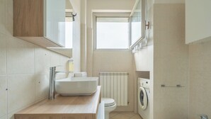 A modern bathroom with a wooden vanity, a sink, a toilet, a washing machine, and a bidet. - Apartment in the center of Bergamo and at the foot of the city high with private parking (Bergamo)