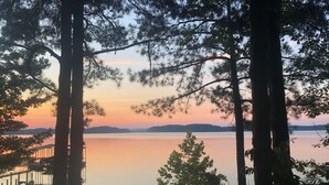 Una vista tranquilla su un lago, incorniciata da alberi alti, con un pontile che si protende sull'acqua.