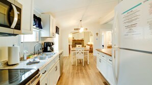 Una cucina moderna con mobili bianchi, forno a microonde integrato, macchina da caffè e zona pranzo con tavolo e sedie.