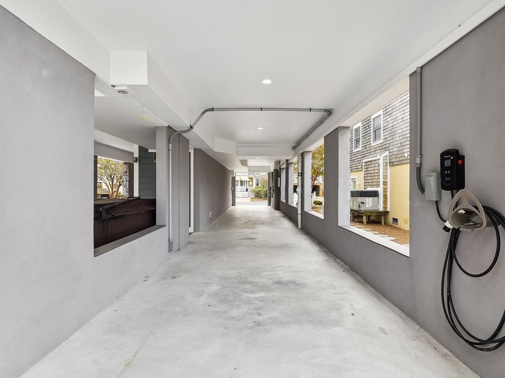 A corridor with a concrete floor, white walls, and a window on the right side.