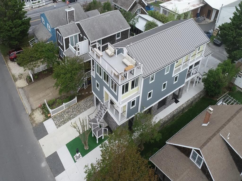 A multi-story residential building with a flat roof, a balcony on the second floor, and a visible staircase leading to the upper levels.