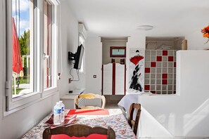 Een kamer met een eettafel, stoelen, een bed, een televisie en een douchehoek.