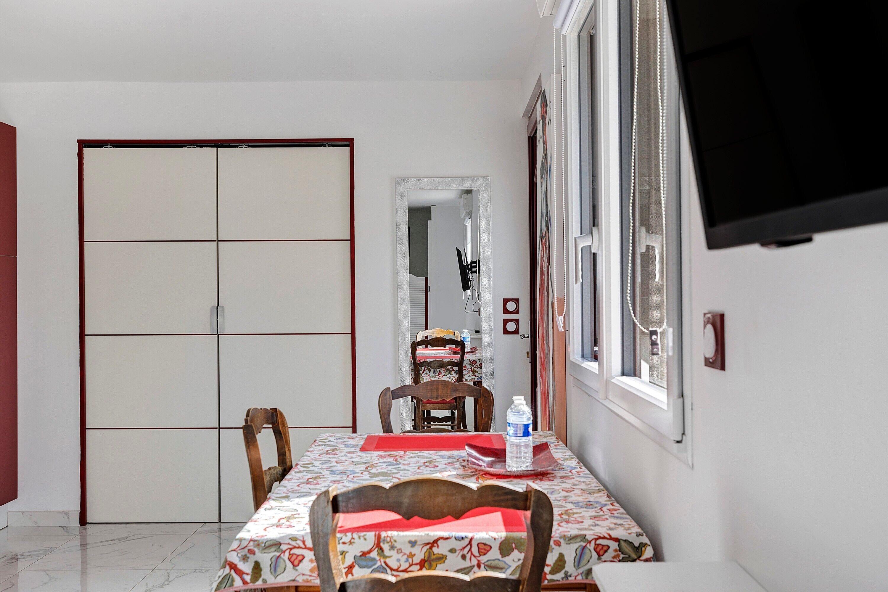 A dining area with a table, chairs, a water bottle, and a TV on the wall.