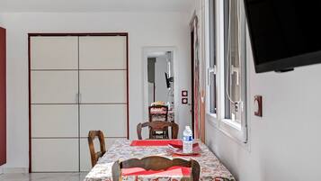 A dining area with a table, chairs, a water bottle, and a TV on the wall.
