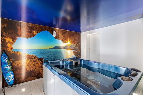 A spa area with a hot tub, a mural of a sunset over the ocean, and a surfboard.. House on the Loire with Pool and Jacuzzi