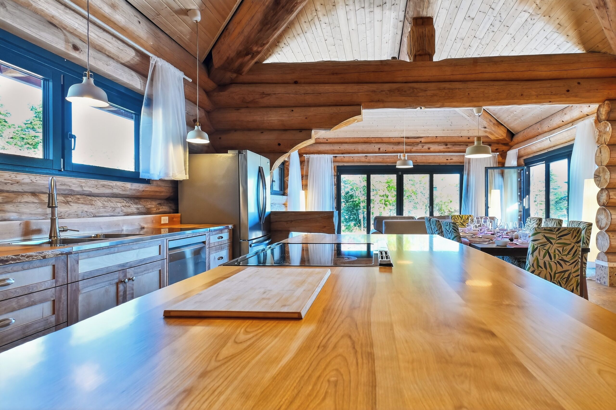 A spacious kitchen with wooden cabinets, a large island, and pendant lighting.