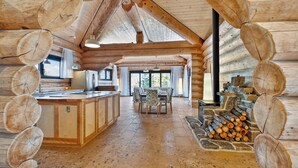 L’intérieur d’une cabane en rondins comprend un espace central dédié à la salle à manger, une cuisine et une cheminée en pierre.