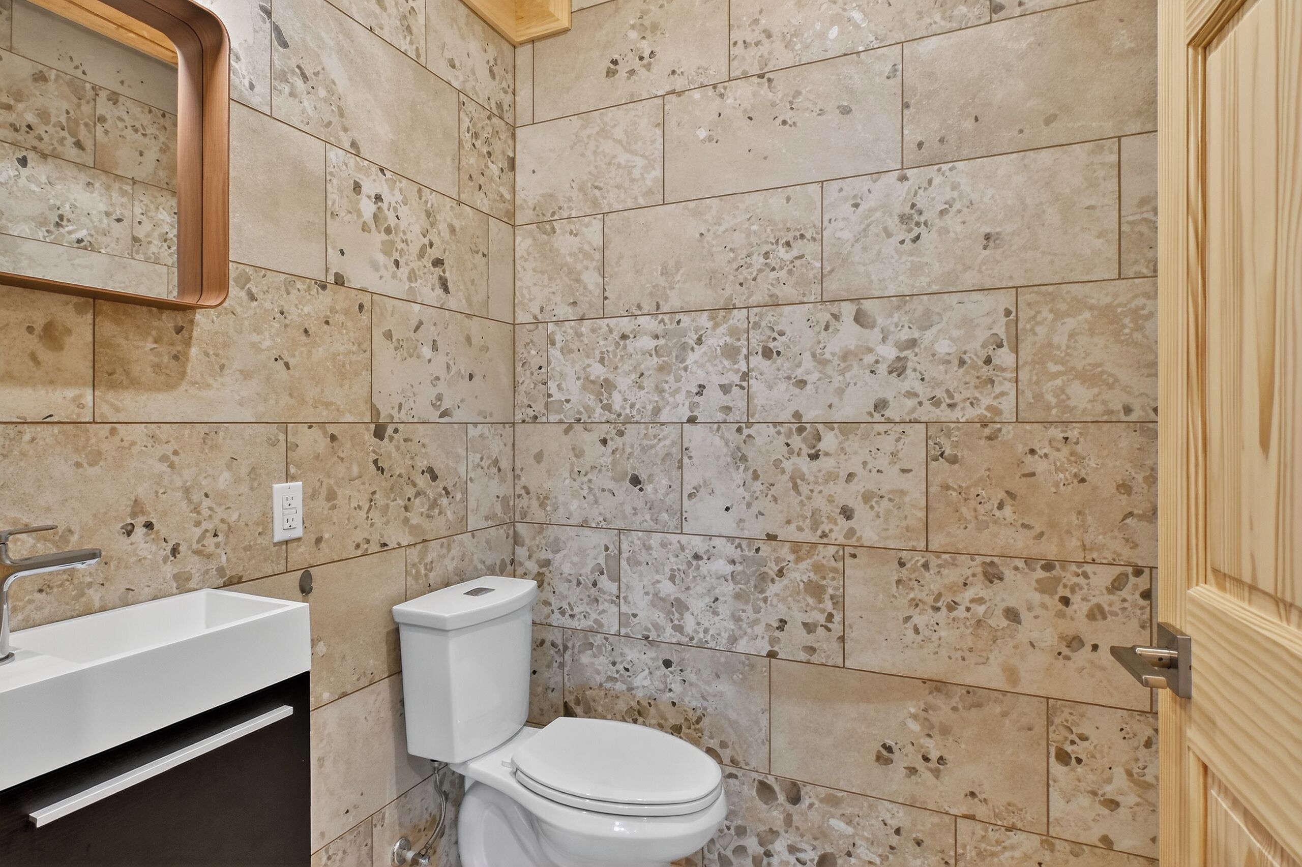 Un bany amb un lavabo, vàter i mirall blancs.