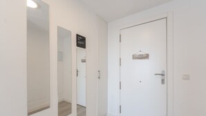 A hallway with a white door, a mirror, and a sign above the door.