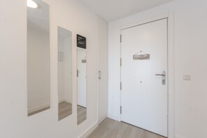 Un pasillo con una puerta blanca, un espejo y un cartel sobre la puerta.