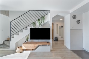 Una sala de estar moderna con una escalera, un televisor de pantalla plana y una mesa de centro de madera.