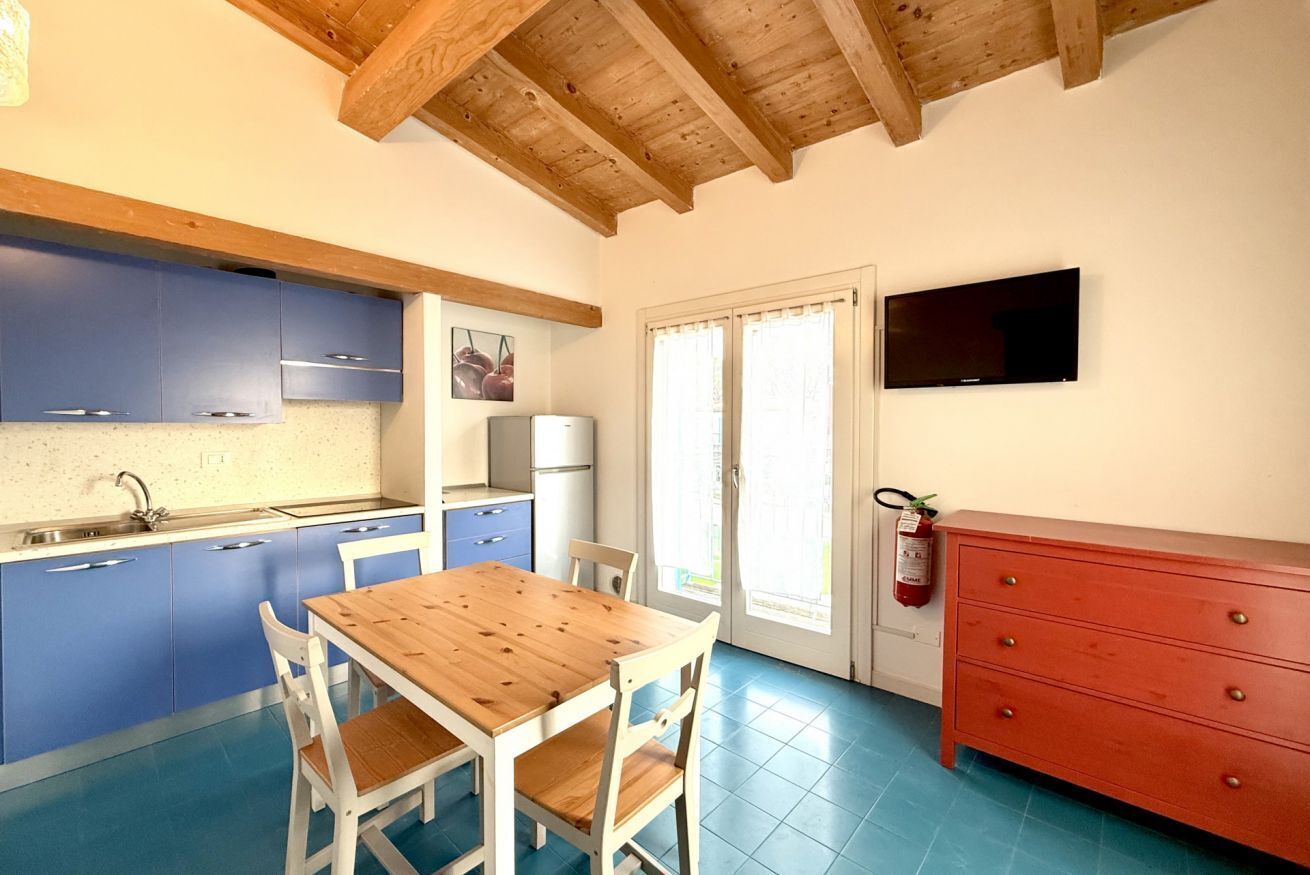 Una cocina con armarios azules, una mesa de madera y un aparador rojo.