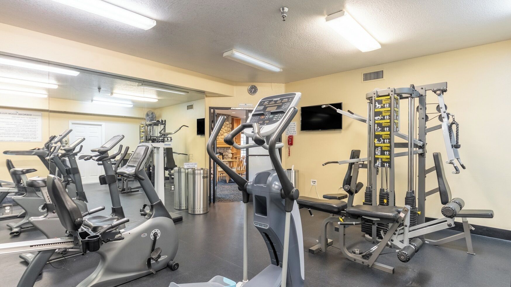 Un gimnasio con diversos equipos de ejercicio, incluyendo cintas de correr, bicicletas estáticas y máquinas de pesas.