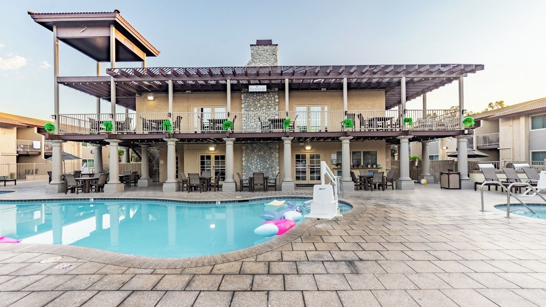 Ein Hotel mit Poolbereich, Außenbereich zum Sitzen und einer überdachten Terrasse.