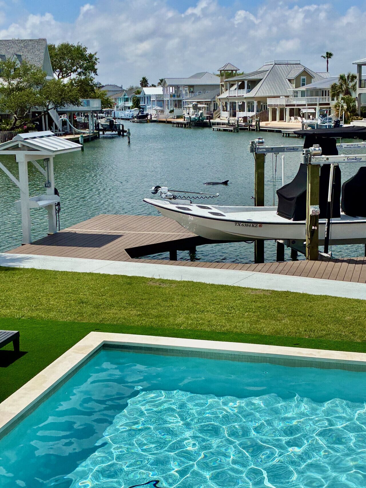 A marina with boats docked, a swimming pool, and waterfront buildings.