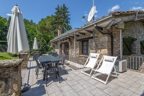 Een stenen gebouw met terras, tuinmeubels en een schotelantenne.