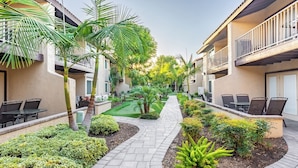 A courtyard with outdoor seating, palm trees, and a well-maintained garden path.