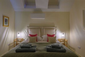 Habitació d'hotel amb un llit, dues làmpades de nit, un capçal amb un disseny estampat i dues tovalloles al llit.