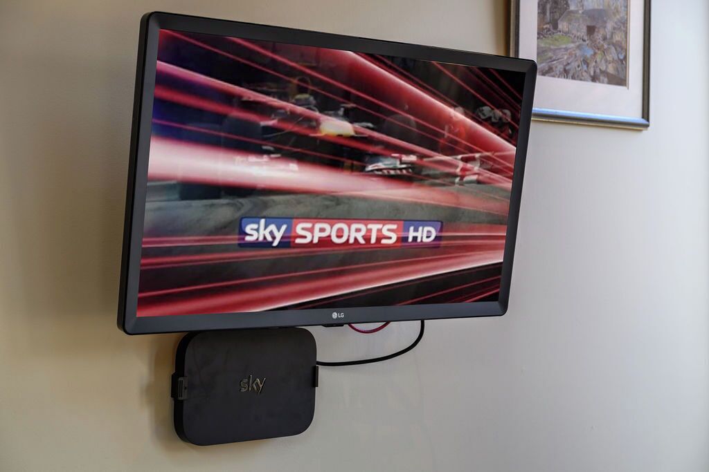 A flat-screen TV mounted on a wall displaying a racing event, with the text 'Sky Sports HD' visible.