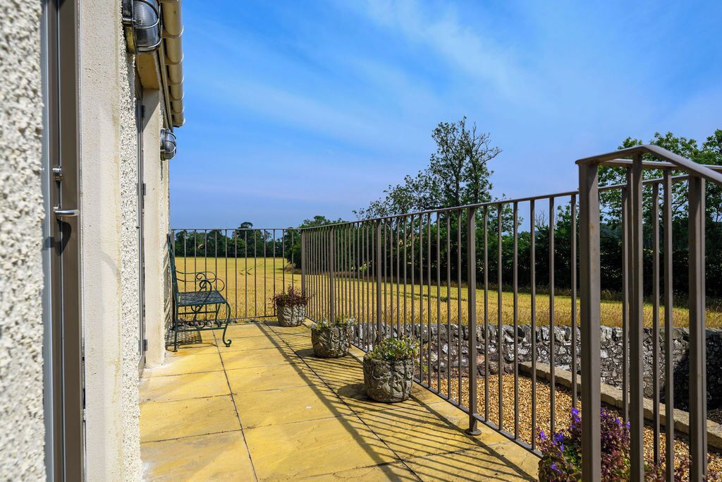 Un patio con pavimento giallo, ringhiera in metallo e piante in vaso.