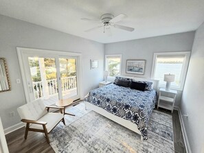 Quarto com cama, cadeira, escrivaninha e janela com vista.