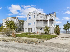 A two-story residential building with a balcony, a small porch, and a solar panel on the roof. - Spacious Beach House | Decks & Pool + Beach Nearby (Bethany Beach)