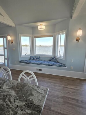 A room with a bay window seating area, white chairs, and a dining table. - Spacious Beach House | Decks & Pool + Beach Nearby (Bethany Beach)