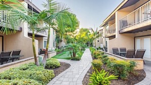 A courtyard with outdoor seating, palm trees, and a well-maintained garden path. - Anaheim | Romantic Disney Retreat | Pool + Parks (Anaheim)