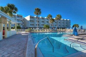 Un hotel con piscina, palmeras y un cielo azul despejado.