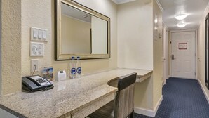 A hotel reception area with a marble counter, a telephone, a mirror, and two water bottles. - Sunset Cove – Tampa Sunsets from Your Balcony (Tampa)