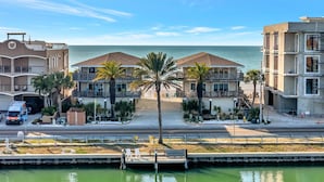A beachfront hotel with multiple balconies, palm trees, and a view of the ocean. - Beachfront 3B Condo | Walk right onto the sand! (Indian Rocks Beach)