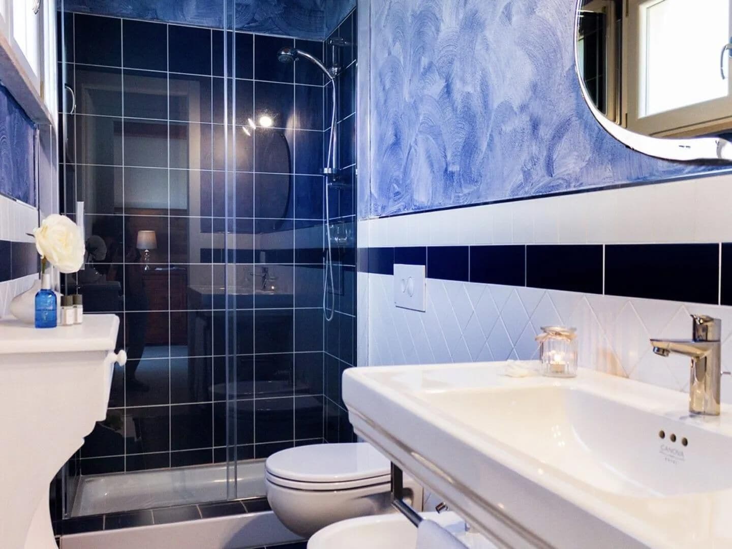 Moderni kylpyhuone, jossa on lasinen suihkuseinä, valkoinen pesuallas ja wc-istuin.