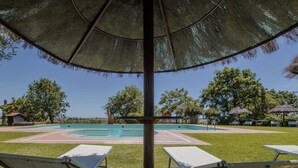 Ein Poolbereich mit Liegestühlen, einer Pergola und Blick auf die umliegende Landschaft.