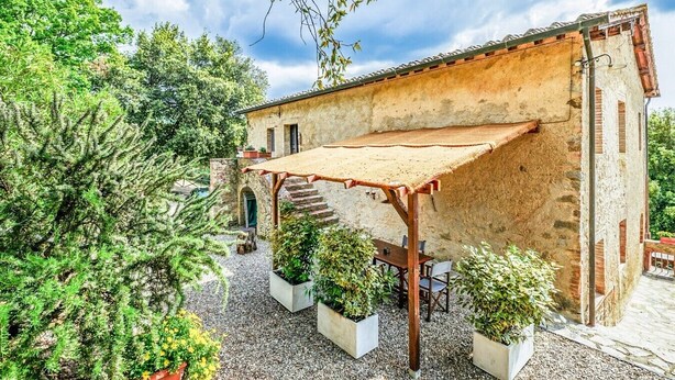 A rustic stone building with a wooden pergola, surrounded by potted plants and a gravel path. - Tenuta della Selva - Castellaccio 7 (Murlo)