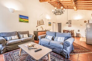 A living room with two sofas, a coffee table, a chandelier, and a dining area. - Tenuta della Selva - Castellaccio 7 (Murlo)
