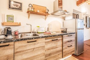 A modern kitchen with a marble countertop, wooden cabinets, a stainless steel refrigerator, and a built-in oven. - Tenuta della Selva - Castellaccio 7 (Murlo)