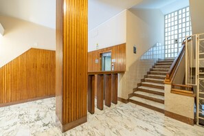 A modern interior with a marble floor, wooden paneling, and a staircase with a glass railing. - Happy Tourist by Wonderful Italy (Sanremo)