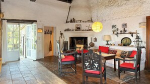 A rustic interior with a stone fireplace, wooden furniture, and a view through an open door. - Tsoupis Villa (Kentroma)