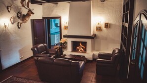 Un salon avec des canapés en cuir, une cheminée et des têtes d’animaux empaillées accrochées au mur.