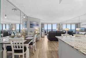 Eine moderne Küche mit Marmorarbeitsplatte, Holzboden und einem Essbereich mit weißen Stühlen und einem Tisch.