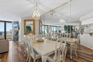 A spacious dining area with a large table and chairs, a chandelier, and a large mirror. - 🌊Gorgeous Ocean Views | Oceanfront Complex | Sand Dollar 1105🌊 (Daytona Beach Shores)