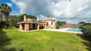 Una casa con facciata in pietra, piscina e prato curato.