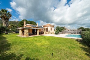 Une maison avec une façade en pierre, une piscine et une pelouse bien entretenue.