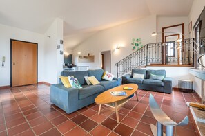 A living room with two sofas, a wooden coffee table, and a staircase with a wrought iron railing. - Villa Ulivi 10 – Is Molas Golf Resort (Is Molas)